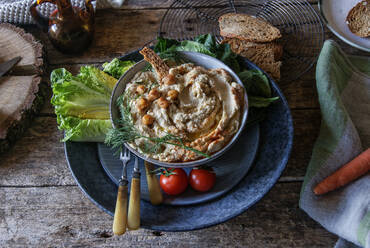 Hände nehmen Teller mit köstlichem Artischocken-Hummus - ADSF02386