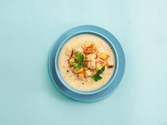 Cauliflower potato soup puree in blue bowl on blue minimalistic background. Top view flat lay. Copy space - ADSF02428