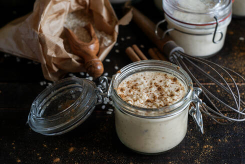 Gläser mit köstlichen süßen Dessert von Reis mit Milch und Zimt auf schwarzen Tisch mit Kochen Zutaten komponiert - ADSF02437