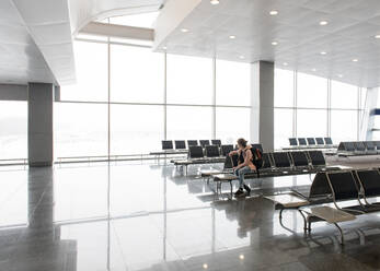 Side view of woman sitting and resting on bench in terminal in Thailand. - ADSF02473