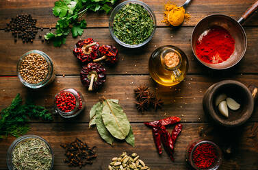 Assorted spices and herbs and bottle of oil placed on wooden tabletop - ADSF02485