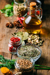 Assorted spices and herbs and bottle of oil placed on wooden tabletop - ADSF02487