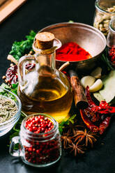 Assorted spices and herbs and bottle of oil placed on wooden tabletop - ADSF02494