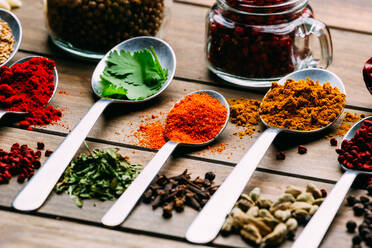 Bunch of assorted spices placed in order on lumber tabletop near bottle of oil - ADSF02501