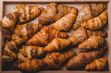 From above of assorted golden baked croissants with different toppings on wooden board. - ADSF02518