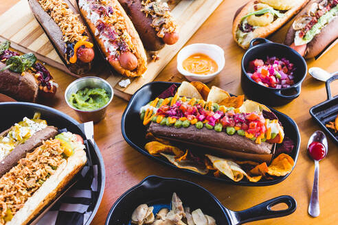 Auf einem Holztisch wird eine große Menge an leckeren Hot Dogs und Snacks serviert. - ADSF02535