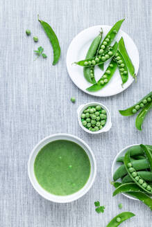 Von oben geschälte Erbsen aus den Schoten und grüne Cremesuppe auf dem Tisch. - ADSF02591