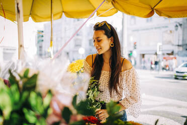 Junge Frau kauft einen Blumenstrauß in einem Blumenladen - DCRF00481