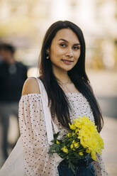Young woman with bouquet in bag in city - DCRF00486