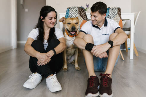 Pärchen mit Hund auf dem Boden sitzend zu Hause - EGAF00444