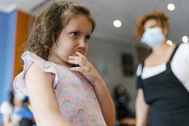 Upset girl looking away t hairdresser in hair salon during pandemic - EGAF00475