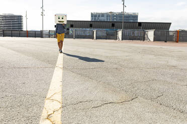 Junge mit Robotermaske auf der Straße in der Stadt an einem sonnigen Tag - VABF03140