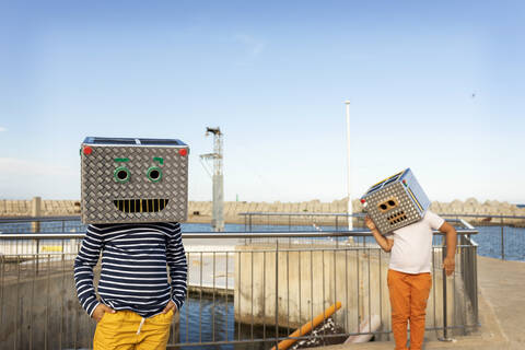 Boys wearing robot costumes standing on footpath against clear blue sky stock photo