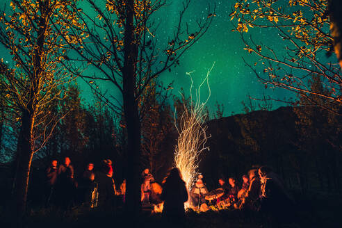 Gruppe von Menschen, die authentische Rituale um brennende und funkelnde Feuer in dunklen Wäldern mit Sternenhimmel - ADSF02655