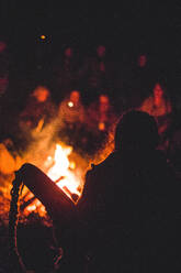Eine Gruppe von Menschen versammelt sich um ein Feuer im Wald - ADSF02657