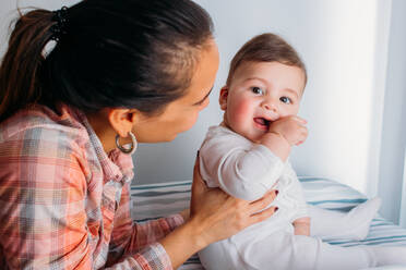 Junge Frau hält entzückendes Baby, während sie Zeit im Kinderzimmer verbringt - ADSF02726