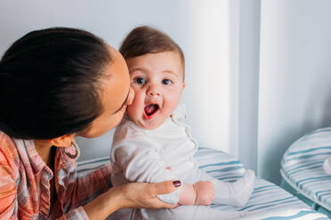 Junge Frau hält entzückendes Baby, während sie Zeit im Kinderzimmer verbringt - ADSF02728