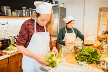 Hübsche Köche Frauen stehen und arbeiten mit Salat auf Küche des Restaurants. - ADSF02753