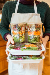 Crop unrecognizable cook holding containers with salad in cafe. - ADSF02758