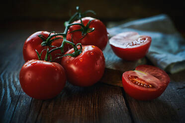 Nahaufnahme Bündel von nassen reifen Tomaten in der Nähe von Serviette auf Holz Tischplatte platziert - ADSF02772