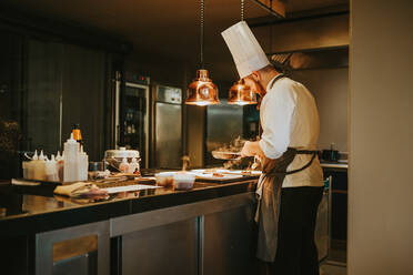 Seitenansicht einer Person, die ein Gericht im Restaurant zubereitet. Horizontale Innenaufnahme. - ADSF02830