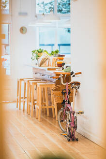 Ein rosafarbenes Fahrrad, das an der Gemüsetheke eines Cafés abgestellt ist. - ADSF02866