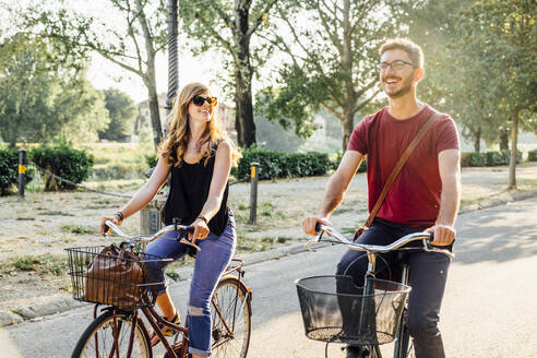 Glückliches Paar auf Fahrrädern auf der Straße im Park am Wochenende - SBAF00024