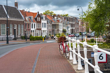 Niederlande, Nordholland, Haarlem, Fahrrad am Geländer der Kanalbrücke geparkt, mit Häusern entlang der Straße Hooimarkt im Hintergrund - TAMF02544