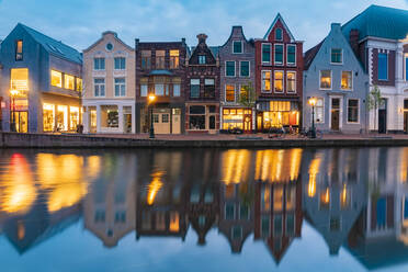 Niederlande, Südholland, Leiden, Reihe historischer Stadthäuser, die sich in der Abenddämmerung im Rheinkanal spiegeln - TAMF02606