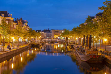 Niederlande, Südholland, Leiden, Brücke über den beleuchteten Nieuwe-Rijn-Kanal in der Abenddämmerung - TAMF02618