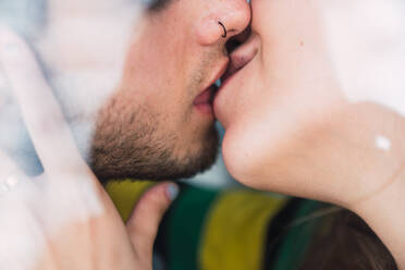 Closeup shot of young unrecognizable couple kissing each other at home throughout a windows glass - ADSF02923