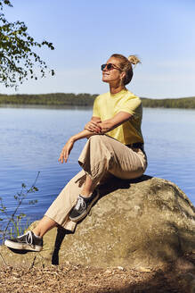 Mittlere erwachsene Frau mit Sonnenbrille an einem See im Tiveden-Nationalpark, Schweden - UKOF00013