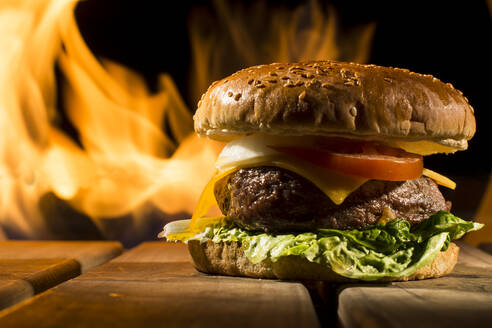Leckere Burger mit großen Kotelett auf Holztisch auf dem Hintergrund des Feuers liegen - ADSF02932