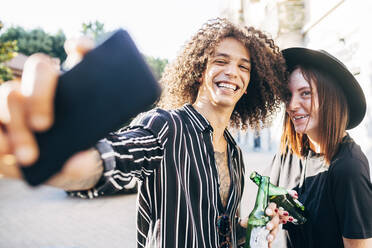 Cheerful man taking selfie with girlfriend while standing in city - MEUF01573