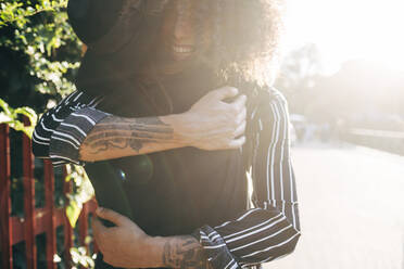 Loving couple embracing while standing in park on sunny day - MEUF01588