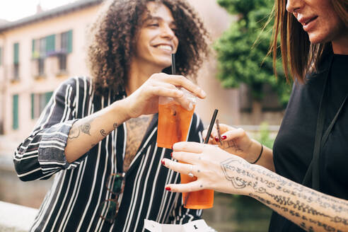 Nahaufnahme eines glücklichen Paares, das mit Getränken anstößt, während es sich in der Stadt amüsiert - MEUF01594