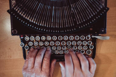 From above shot of hands of anonymous elderly person typing on keyboard of vintage typewriter - ADSF02964