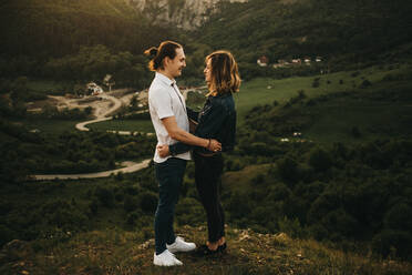 Cute couple hugging and toughing foreheads while standing on background of beautiful valley and mountains - ADSF02979