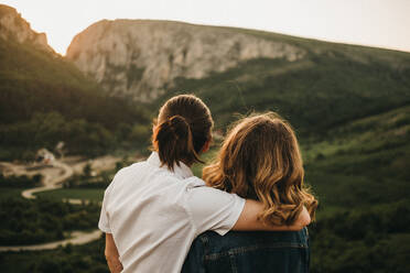 Cute couple hugging and toughing foreheads while sitting on rocky slope on background of beautiful valley and mountains - ADSF02980