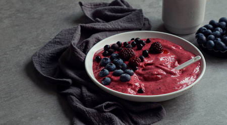 Smoothy of fresh bog blueberries and raspberries in bowl near napkin - ADSF03045