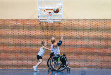 Disabled sport men and little girl in action while playing indoor basketball - ADSF03052