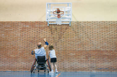 Disabled sport men and little girl in action while playing indoor basketball - ADSF03054