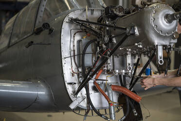 Die Hände eines Flugzeugmechanikers, der den Motor eines kleinen Flugzeugs im Hangar repariert - ADSF03104