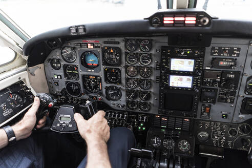 Unbekannter Mann mit Headset steuert Flugzeug?allein im Cockpit eines modernen Flugzeugs sitzend - ADSF03108