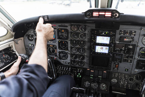 Unbekannter Mann mit Headset steuert Flugzeug?allein im Cockpit eines modernen Flugzeugs sitzend - ADSF03109