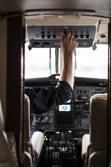 Unbekannter Mann mit Headset steuert Flugzeug?allein im Cockpit eines modernen Flugzeugs sitzend - ADSF03110
