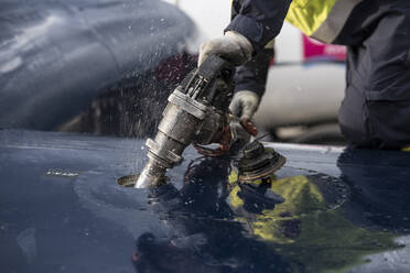 Crop man in uniform fueling modern plane while working on airfield - ADSF03111