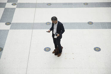 Businessman using smartphone at train station - PMF01215