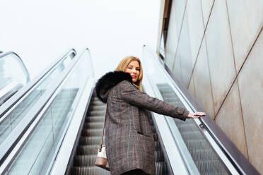 Blondes Mädchen klettert Rolltreppe im Einkaufszentrum - ADSF03155