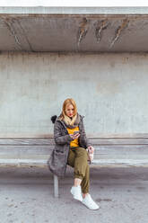 Porträt einer blonden Frau, die ihr Mobiltelefon auf der Straße benutzt - ADSF03159